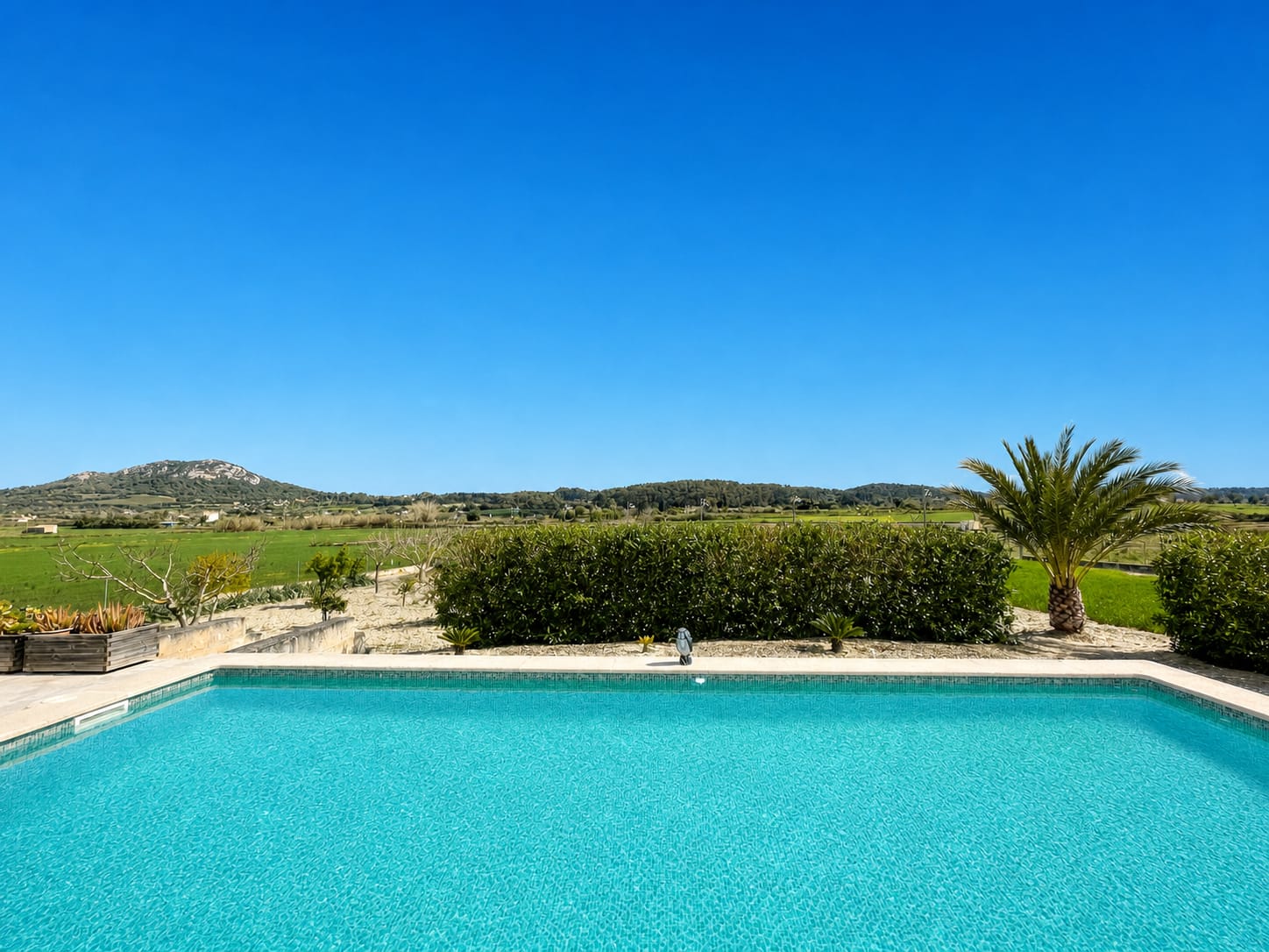 Pool einer Finca auf Mallorca unter wolkenfreiem blauem Himmel